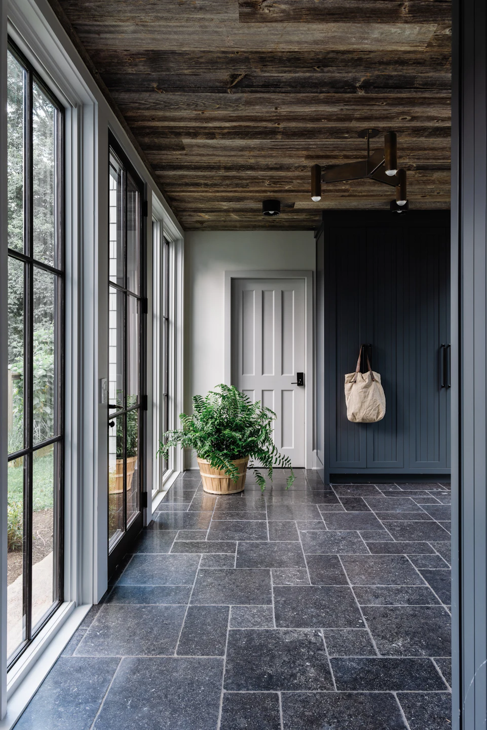 Custom breezeway and mudroom with bluestone floor, reclaimed wood ceiling, and floor-to-ceiling steel windows in the Fairfield Transitional home