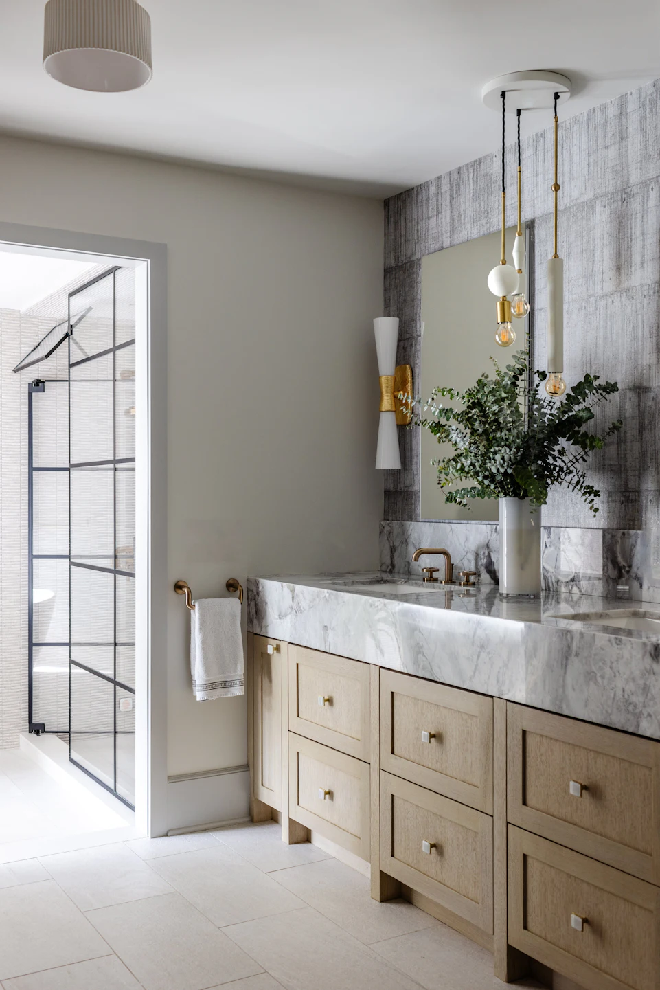 Luxury primary bathroom with double marble vanity, white oak cabinets, brass fixtures, and aluminum-framed glass shower in the Fairfield Transitional custom home
